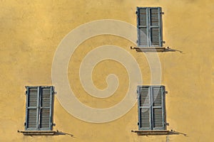 Closed green windows on yellow wall of old house in Florence cit