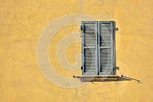 Closed green windows on yellow wall of old house in Florence cit