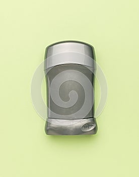 A closed grey tube with deodorant on a light green background