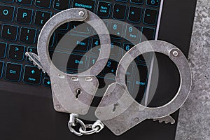 Closed handcuffs on a laptop keyboard close up. Concept on the topic of punishment for digital fraud