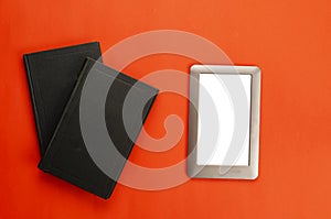 Closed hardcover books and e-book on a red background