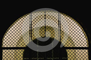 Closed iron mesh arch with illuminated entrance door to the Church at night.