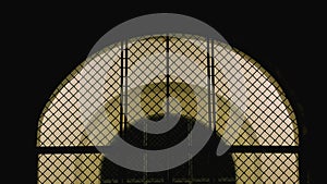 Closed iron mesh arch with illuminated entrance door to the Church at night.