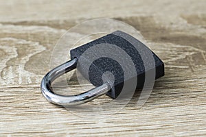 closed iron padlock with a shiny chrome shackle on the wooden surface