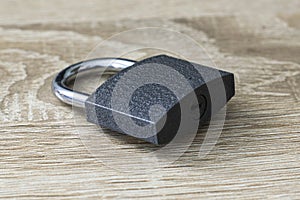closed iron padlock with a shiny chrome shackle on the wooden surface