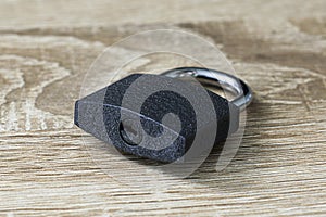 Closed iron padlock with a shiny chrome shackle on the wooden surface