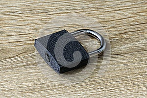 closed iron padlock with a shiny chrome shackle on the wooden surface