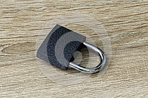 closed iron padlock with a shiny chrome shackle on the wooden surface