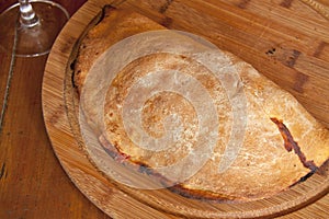 A closed italian pizza calzone on a wooden plate
