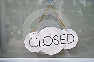 Closed label on the cloud-shaped board, hanging behind the glass door at coffee shop