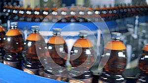 Closed and labeled plastic bottles with beer are moving along the belt