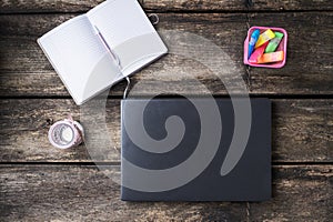 Closed laptop computer, notepad and colorful markers on rustic wooden desk