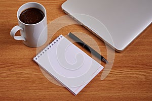 Closed Laptop Beside Empty Journal With Pen And Coffee Mug Over Table. Notebook Computer With Blank Notepad Ballpen
