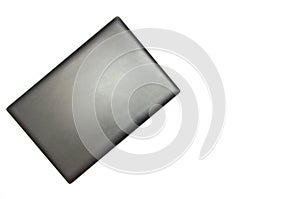 Closed laptop on a white background. View from above. The laptop lies sideways in the upper left corner. Black, graphite, gray,