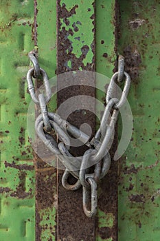 Closed lock with a chain on an old metal door