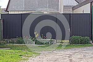 Closed metal door and black iron gate on a fence wall