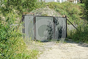 Closed metal gate and door with part of the fence