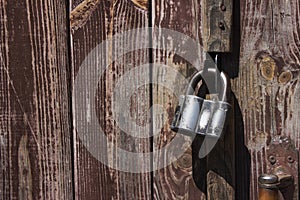 Closed metal lock hanging on the wooden brown old doors