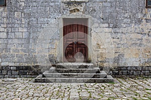 Closed obsolete wooden door and stone bricks steps ancient building