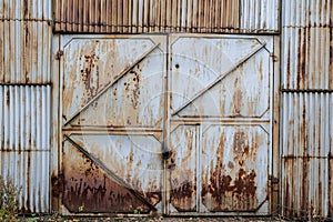 Zavřeno starý rezavý žehlička brána šerpa v vlnitý žehlička stěna. opuštěný průmyslový budova. 