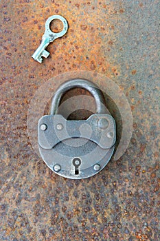 Closed old rusty lock with key lying near on the rusty iron surface. Copy space. Looking for problem solution concept in