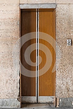 Closed old Soviet wooden elevator doors in the old interior in the style of modernism, with walls lined with travertine