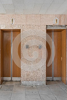 Closed old Soviet wooden elevator doors in the old interior in the style of modernism, with walls lined with travertine