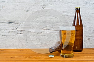 Closed and opened beer bottles with full glass on pub table