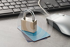 Closed padlock on credit cards and computer mouse and keyboard on the table. Cyber security and protection concept