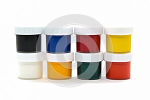 Closed plastic jars with gouache paint of different colors for children`s creativity on white background
