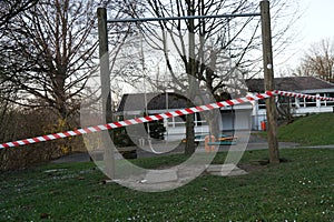 Closed playground with swings due to.  A metal barrier and red-white barrier tape