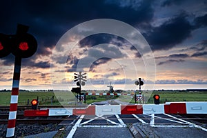 Closed rail crossing at sunrise and windmill