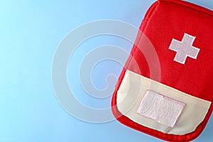Closed red travel first aid kit pouch on the bright blue background. Photo with a copy space