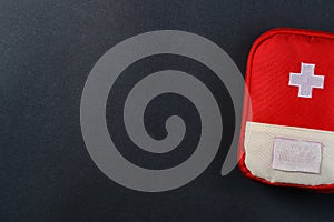 Closed red travel first aid kit pouch on the dark background. Photo with a copy space