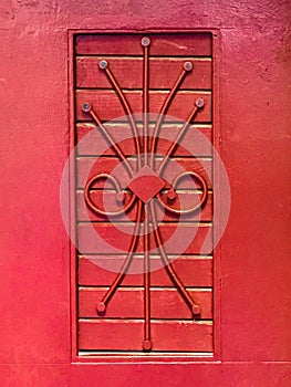 Closed red window with metal ornament, window grill.