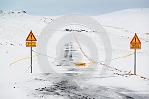 Closed road with attention signs, impassable gravel road in winter, Iceland photo