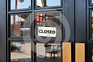 Closed sign board hanging on door of cafe