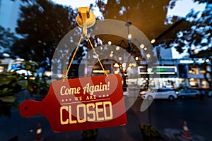Closed sign door hanging on the glass wall inside a restaurant with busy background