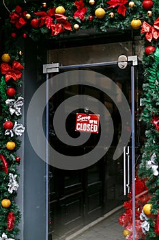Closed sign on front door, decorated with christmas baubles. We are closed due coronavirus