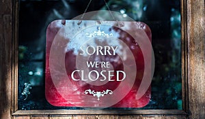 Closed sign over red background in shop window