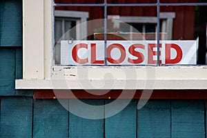 Closed sign in window of green painted wooden building