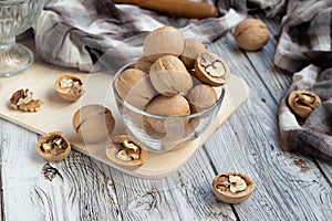 Closed and split walnuts in dishes on a light wooden background, textiles, cutting Board