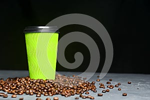 Closed take-out coffee with cup holder. One green cup with coffee beans over black background.