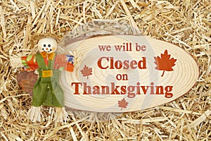 Closed for Thanksgiving message with a scarecrow with wood sign