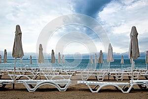 Closed umbrellas and deckchairs on the empty beach