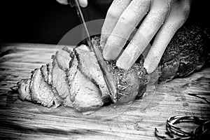 Closed up of chefâ€™s hand slicing tender smoked and grilled beef on wooden board. Beef sliced. Western traditional food.