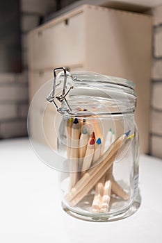 Closed up color pencils in glass jar with lid on white desk
