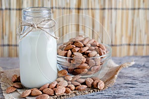 Closed up delicious homemade almond milk in glass bottle with some seed pile in glass bowl