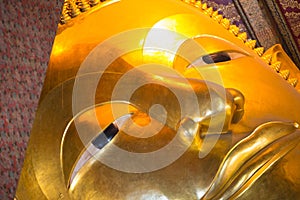 Closed up face of Reclining Buddha gold statue in Wat Pho