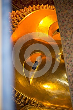 Closed up face from window of Reclining Buddha gold statue. Wat Pho